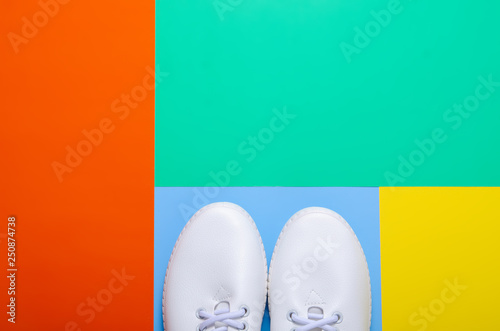Pair of white sneakers on color background, flat lay, top view