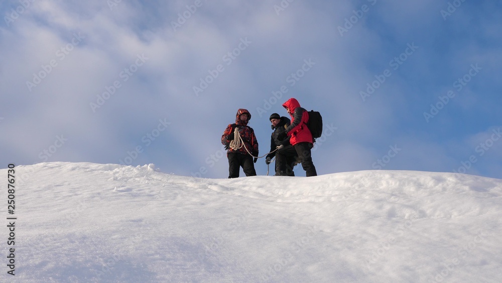 Alpenists team in winter are preparing to descend on rope from mountain. Travelers descend by rope from snowy hill. well-coordinated teamwork in winter tourism.