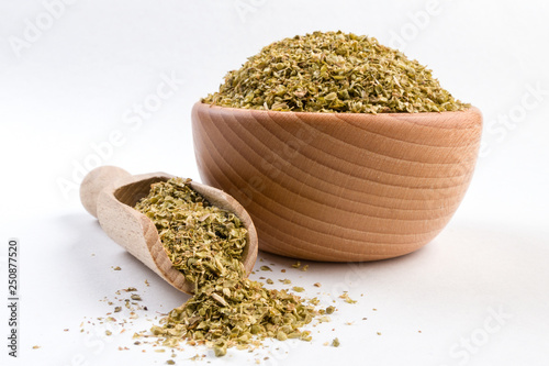 oregano herb in wooden bowl and scoop isolated on white background