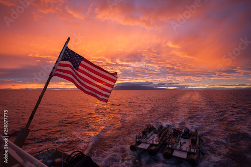 American flag in front of a beautiful ocean sunset landscape
