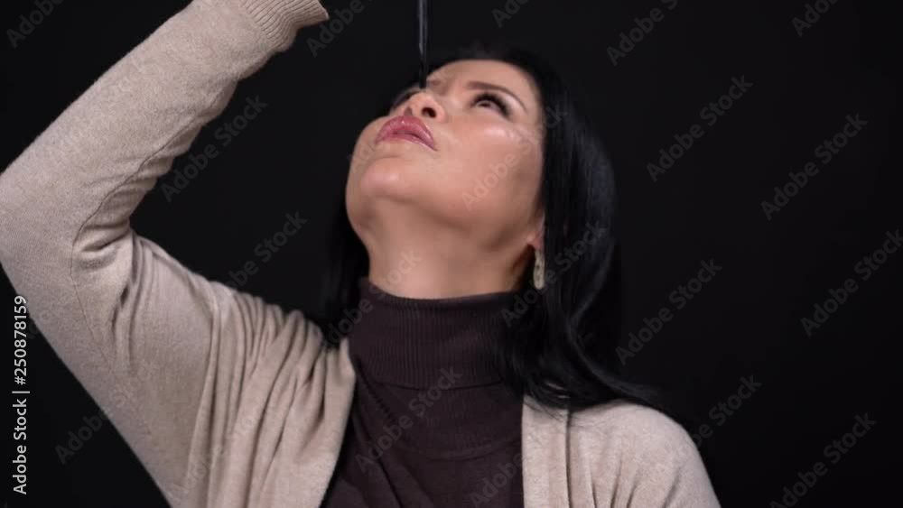 A Brunette Woman with Narrow Eyes on a Black Background Holds the Andle in her Hand. A Brunette Woman with Narrow Eyes on a Black Background Holds the Andle in her Hand.