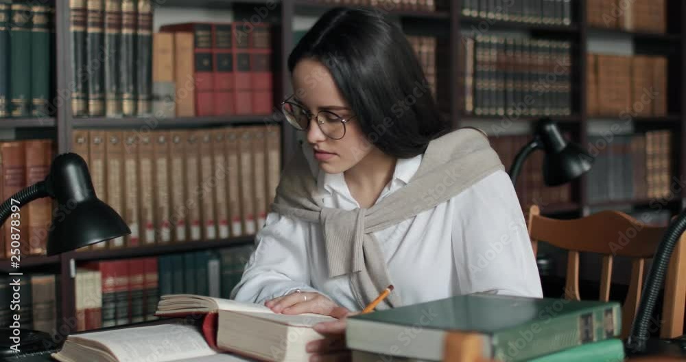 Female university student studying lesson in library Female university student studying lesson in library