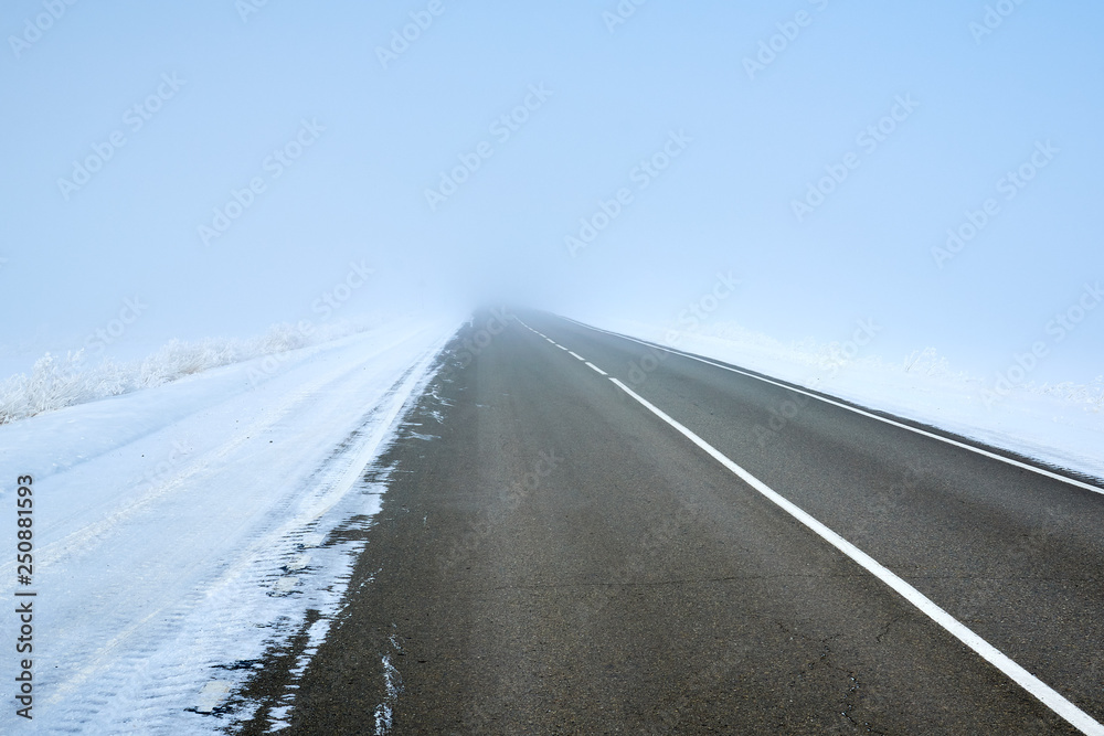 Fototapeta premium scenic view of empty road with snow covered landscape while snowing in winter season.