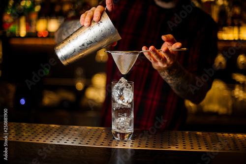 Bartender pouring a Hurricane Punch cocktail from the steel shaker