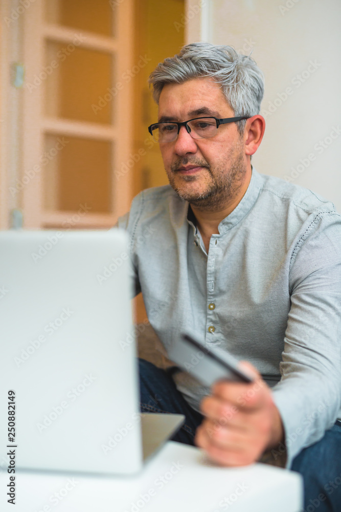 closeup view of middle aged man using credit card for online shopping closeup view of middle aged man using credit card for online shopping