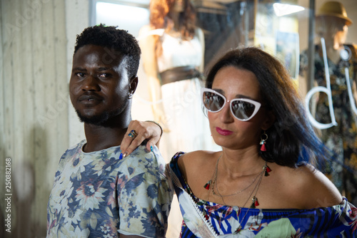 Portrait of happy interracial amorous couple. African man looking at his Caucasian woman. Elegant young couple while strolling through the city. The girl wears sunglasses and puts a hand on the boy's  © Roza_Sean