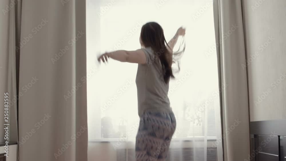 Young girl in pajamas jumping on the bed. Bright light from the window. Young girl in pajamas jumping on the bed. Bright light from the window.