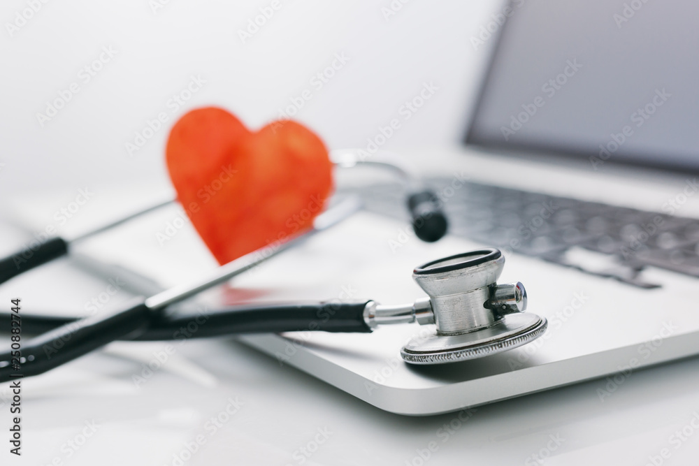 closeup view of stethoscope on laptop with red heart in background. bright image closeup view of stethoscope on laptop with red heart in background. bright image