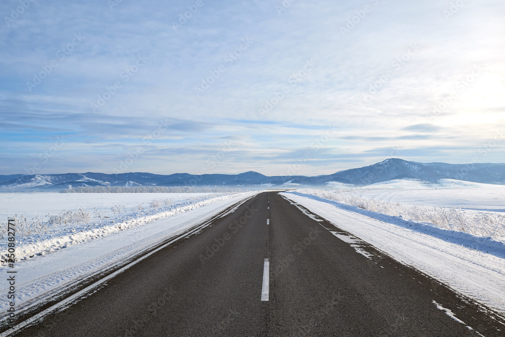 scenic view of empty road with snow covered landscape while snowing in winter season. Blue sky On the horizon. scenic view of empty road with snow covered landscape while snowing in winter season. Blue sky On the horizon.