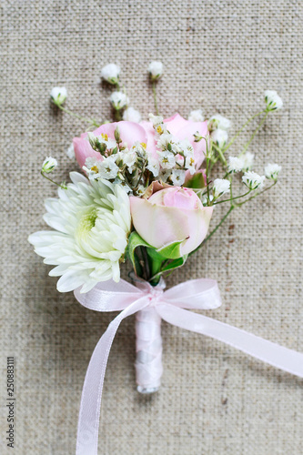 Wedding boutonniere with pink rose, ranunculus and white chrysanthemum.