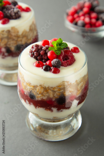 Overnight oats, muesli with berries. Healthy breakfast in glass over grey background. Tasty oatmeals with yogurt.
