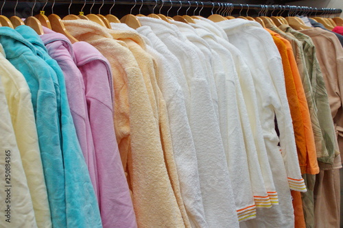 Image of many colorful bathrobes on wooden hangers in the store