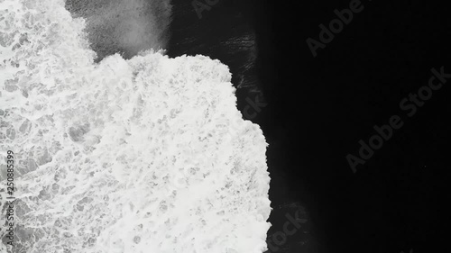 Top down aerial view on a black beach with white waves in Iceland