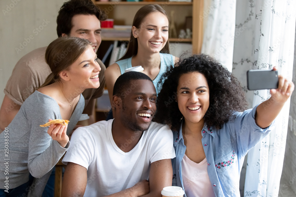 Obraz premium Happy smiling multiracial friends making selfie photo in pizzeria