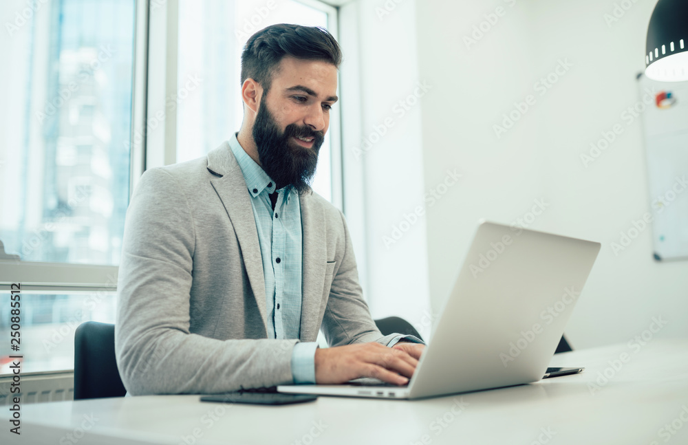 Portrait of young man sitting at his desk in the office Portrait of young man sitting at his desk in the office