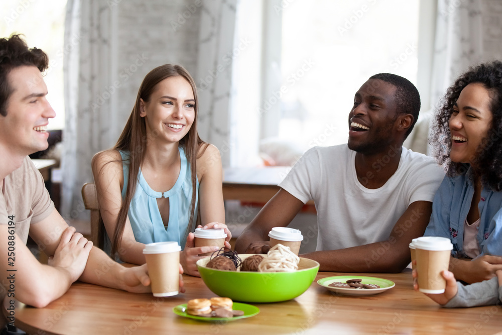 Happy multiracial friends spending free time together in cafe