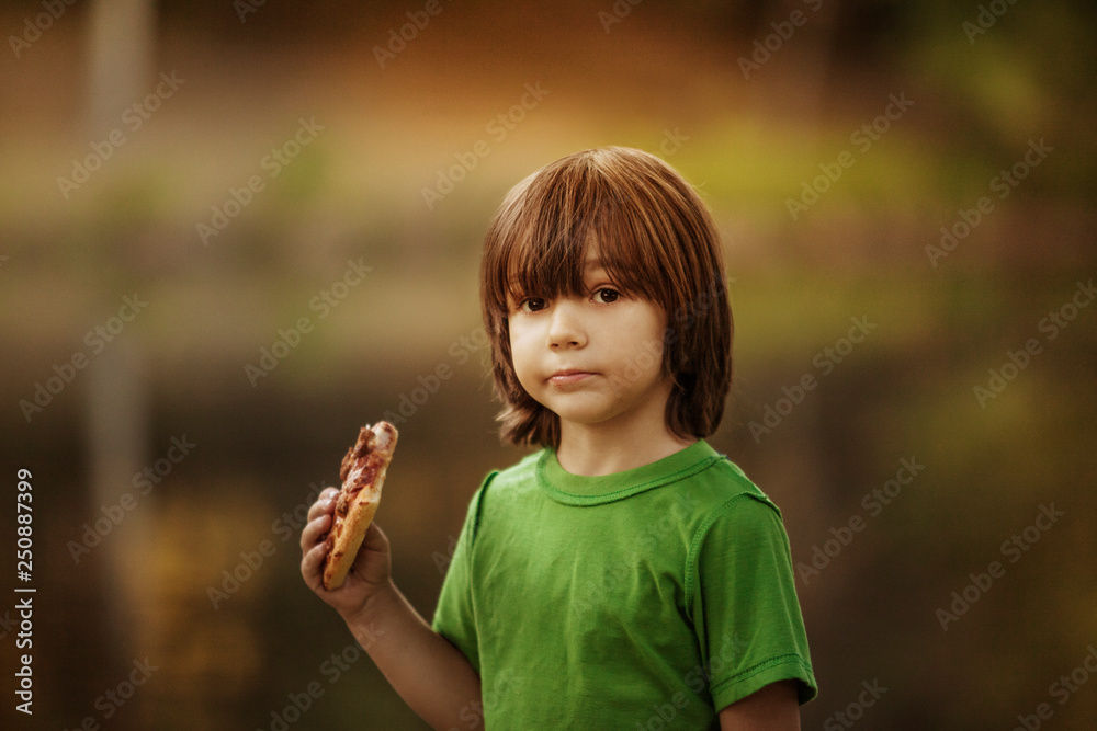 Portrait of boy (4-5) holding slice of pizza 