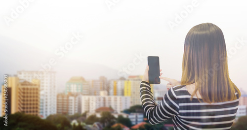 Double exposure of asian woman use smaetphone for connect social network and working with blurred cityscape background. Concept technology and communication