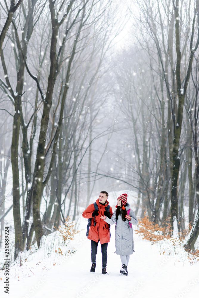 Tourists with backpacks walking at the winter snowy forest and admiring of the landscapes