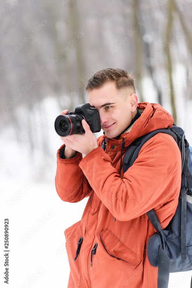 Obraz premium Blonde photograph boy shooting winter landscapes while walking in the forest