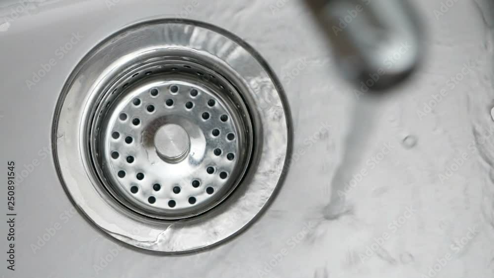 Water down a sink drain. Streaming water in sink. Water stream going down the drain. Water down a sink drain. Streaming water in sink. Water stream going down the drain.