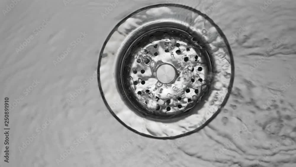 Water down a sink drain. Water stream going down the drain. Water down a sink drain. Water stream going down the drain.