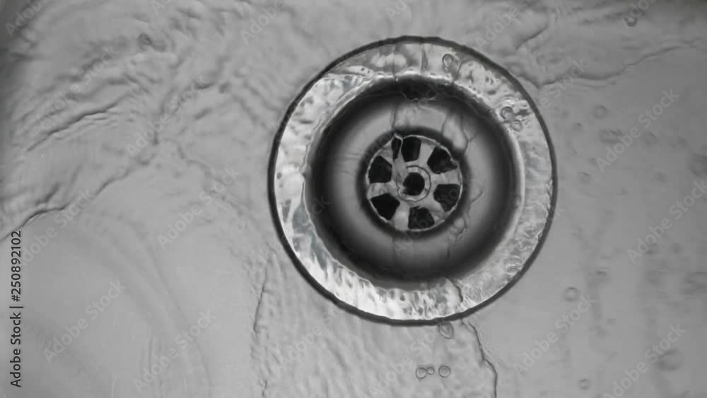 Water down a sink drain. Water stream going down the drain. Water down a sink drain. Water stream going down the drain.