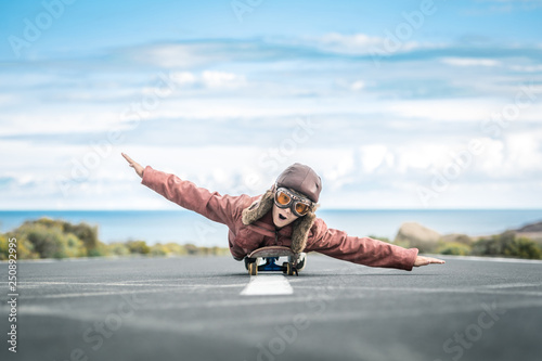 Beautiful child lying skateboard flies vintage pilot suit with hat leather jacket and mask takes off from road central line with sea horizon smiles amused landing taxiing departure arrival. Concept