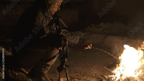 Ugly Dangerous zombie monster Sitting near the bonfire with heavy Cross bow in Dark ruined concrete shelter. Horror Character concept, Armed and grasepainted entity photo