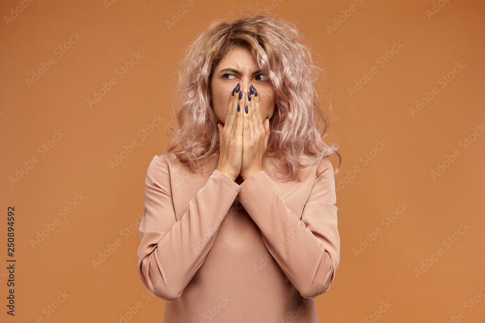 Picture of grimacing displeased disgusted young woman with stylish hairdo pinching nose because of unpleasant smell coming from rotten food in fridge. Stink, disgust, body smelling and odour concept Picture of grimacing displeased disgusted young woman with stylish hairdo pinching nose because of unpleasant smell coming from rotten food in fridge. Stink, disgust, body smelling and odour concept
