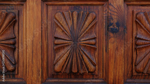 Close-up shot of a carved wooden door with classic stylized motifs forming symmetrical patterns. Ornamental background concept for home ownership, status, privacy or interior design with copy space.