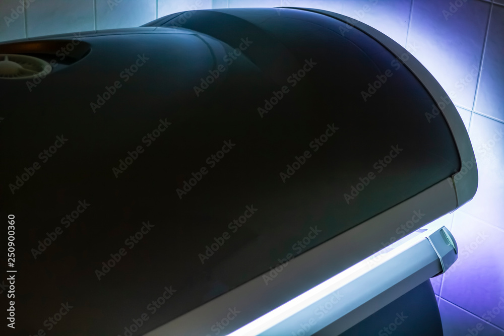 Solarium - tanning bed  with a closed lid and a very beautiful purple-blue alluring lighting.