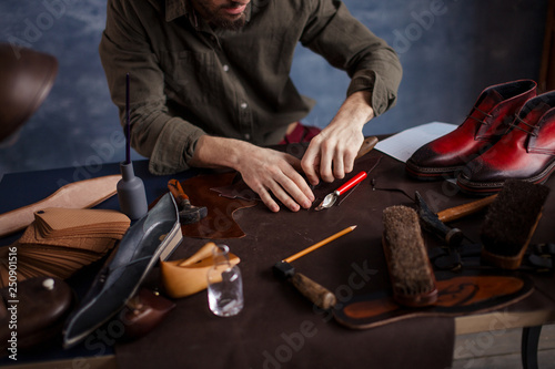 man cutting a pattern for goods, close up cropped photo
