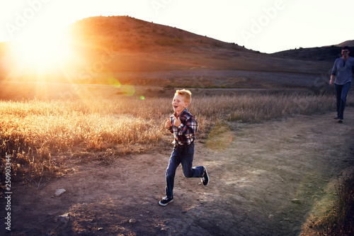 Young boy with father running on country road 