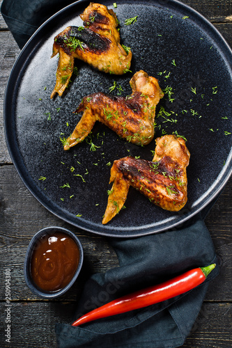 Chicken wings BBQ on the black plate. Black wooden background, side view