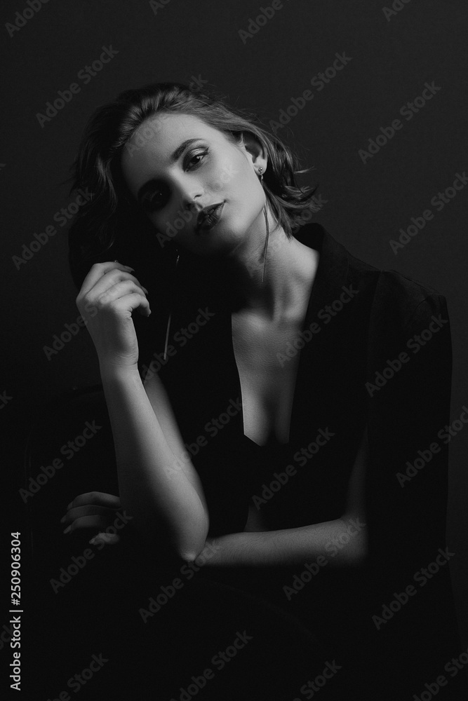 Portrait of wonderful brunette girl with wave hair posing with contrast light. Black and white toning