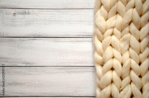 Cozy white scandinavian bedroom interior. Beautiful merino woolen plaid decorated bed and floor, super chunky yarn knitted blanket