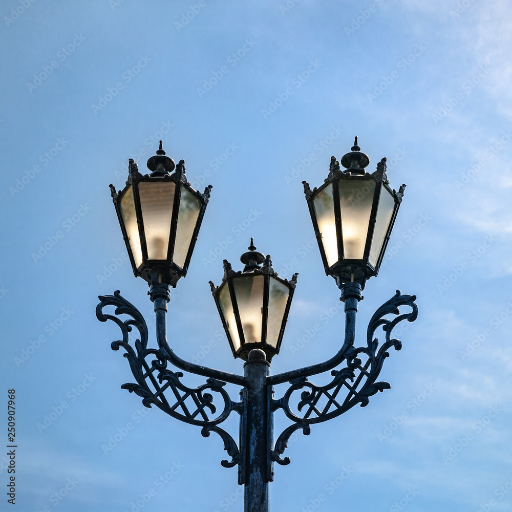 Vintage street lamp against a blue sky.