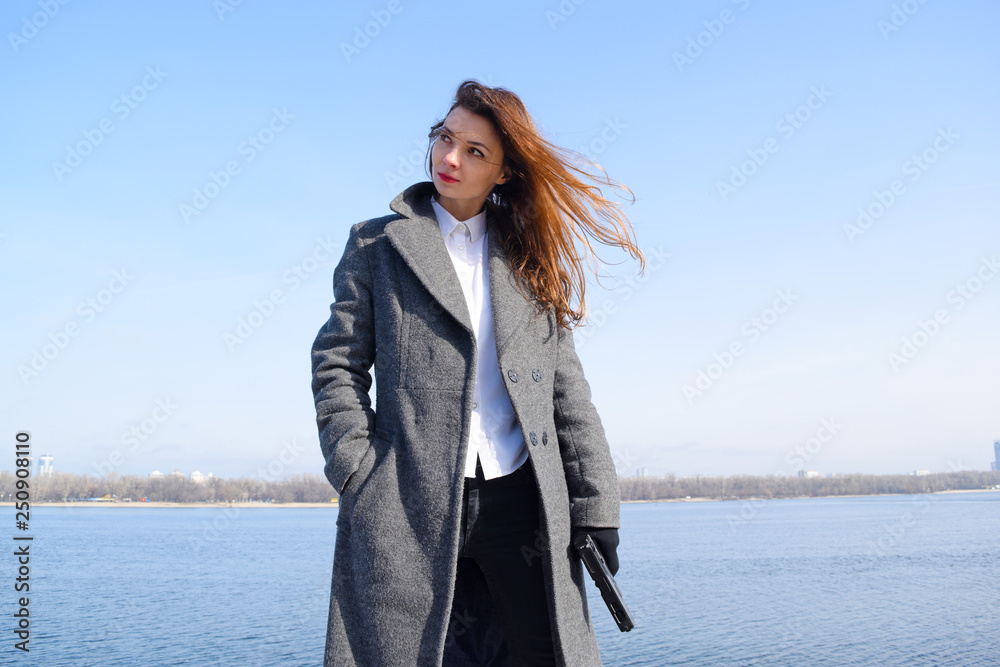 Young woman in a coat shoots over the river in the city. Young woman in a coat shoots over the river in the city.