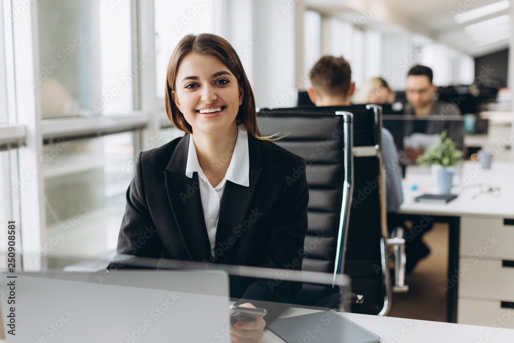 Portrait of a happy businesswoman sitting at her workplace in office Portrait of a happy businesswoman sitting at her workplace in office