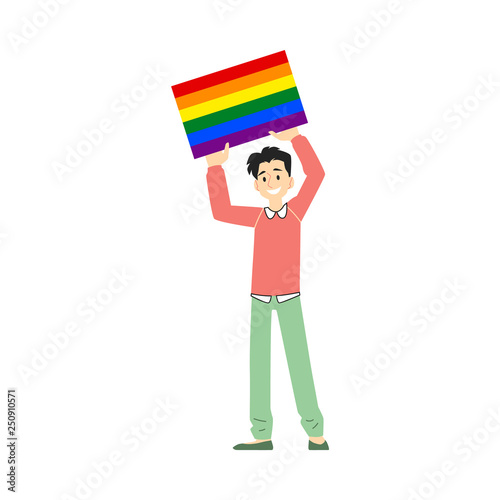 A young smiling white brunet man and gay in pants and sweater holds a poster or a banner with a rainbow.