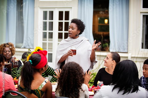 Woman holding drink and talking at family dinner photo