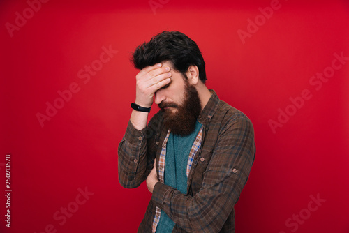 Tablou canvas Close up portrait of disappointed stressed bearded young man in with closed eyes