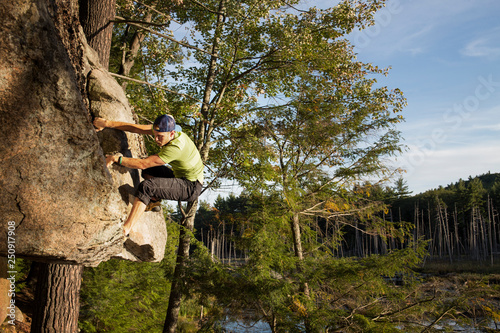 New Hampshire, Pawtuckaway State Park, Young man climbing rock at dusk  photo