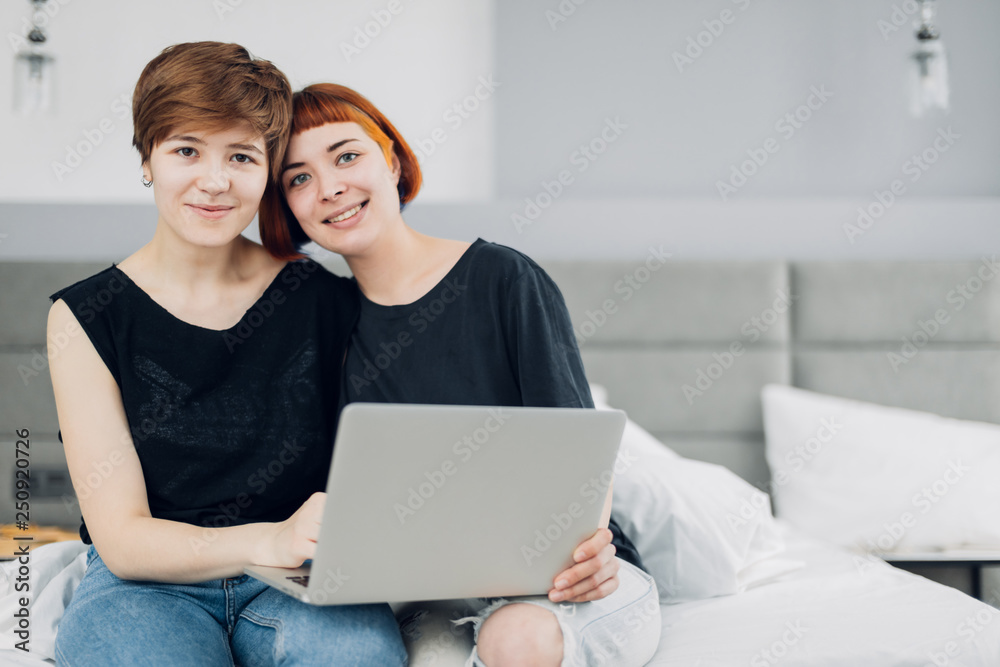 pretty girls sitting in front of the laptop and looking at the camera. close up photo. copy space, friendsgip, gadget concept , free time