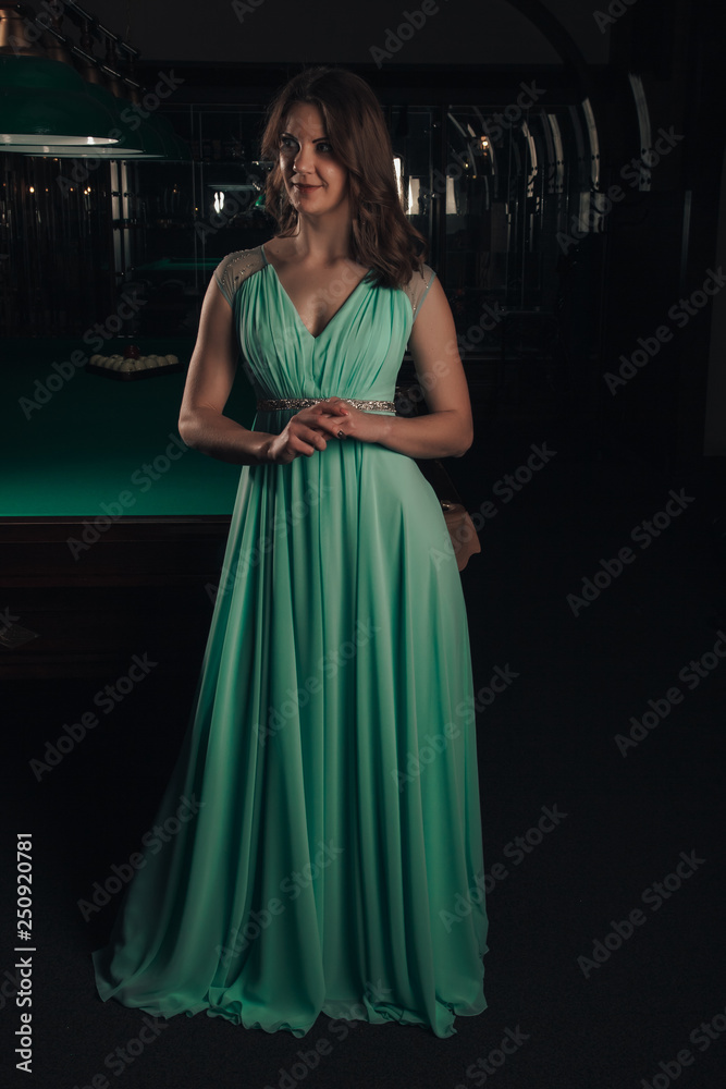 Young woman playing billiards in the dark billiard club Young woman playing billiards in the dark billiard club