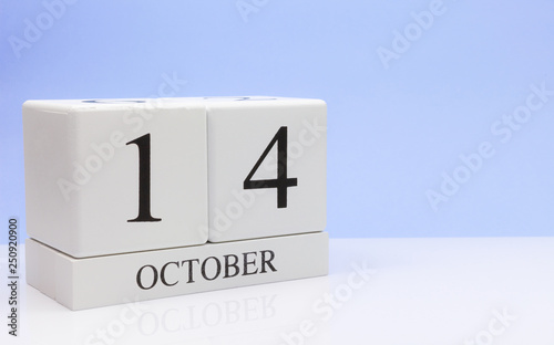 October 14st. Day 14 of month, daily calendar on white table with reflection, with light blue background. Autumn time, empty space for text photo