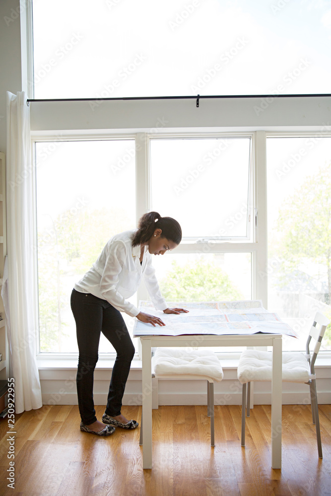 Woman studying blueprints in living room Woman studying blueprints in living room