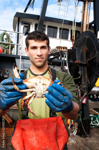 Fisherman holding up crab on fishing boat  photo