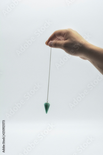 Pendulum dowsing on an isolated white background with a turquoise crystal. photo